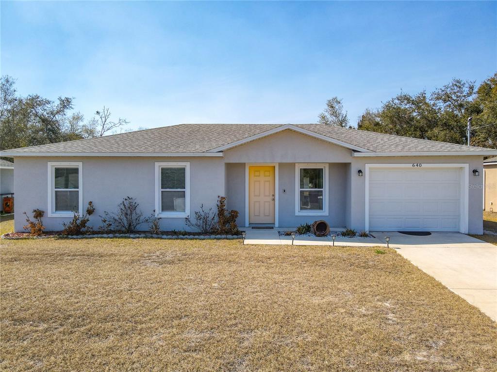 A single-story house with a light gray exterior, a yellow front door, and a garage — 640 CHESTNUT AVENUE, ORANGE CITY, FL