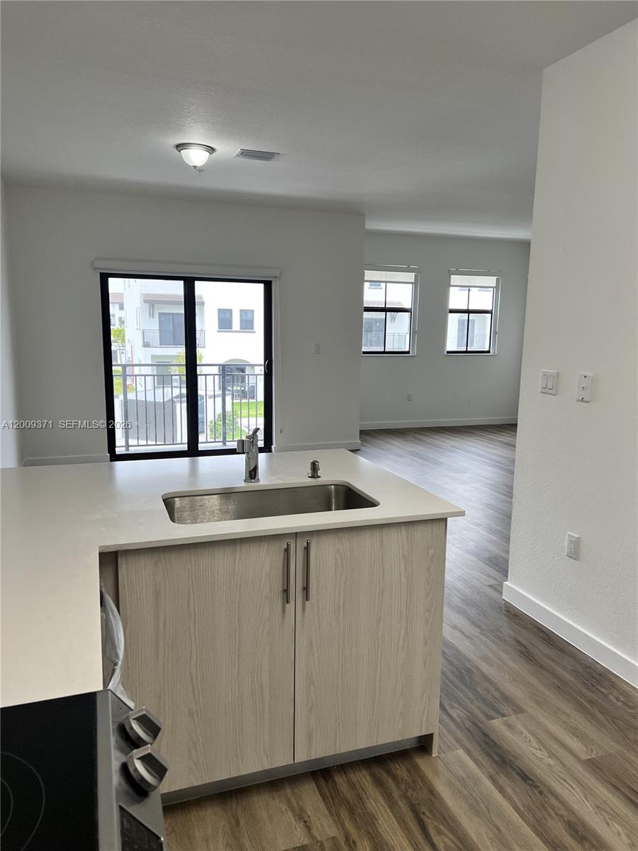 A kitchen island with a stainless steel sink sits before a sliding glass door — 15540 SW 136th St # 206, Miami FL 33196, MIAMI, FL