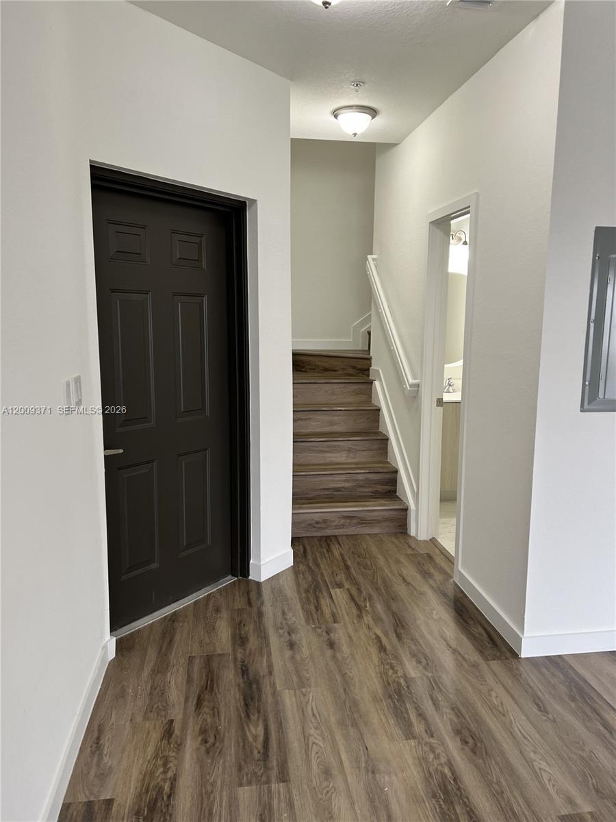 This interior view shows a hallway with wood-look flooring, a dark door, and stairs — 15540 SW 136th St # 206, Miami FL 33196, MIAMI, FL