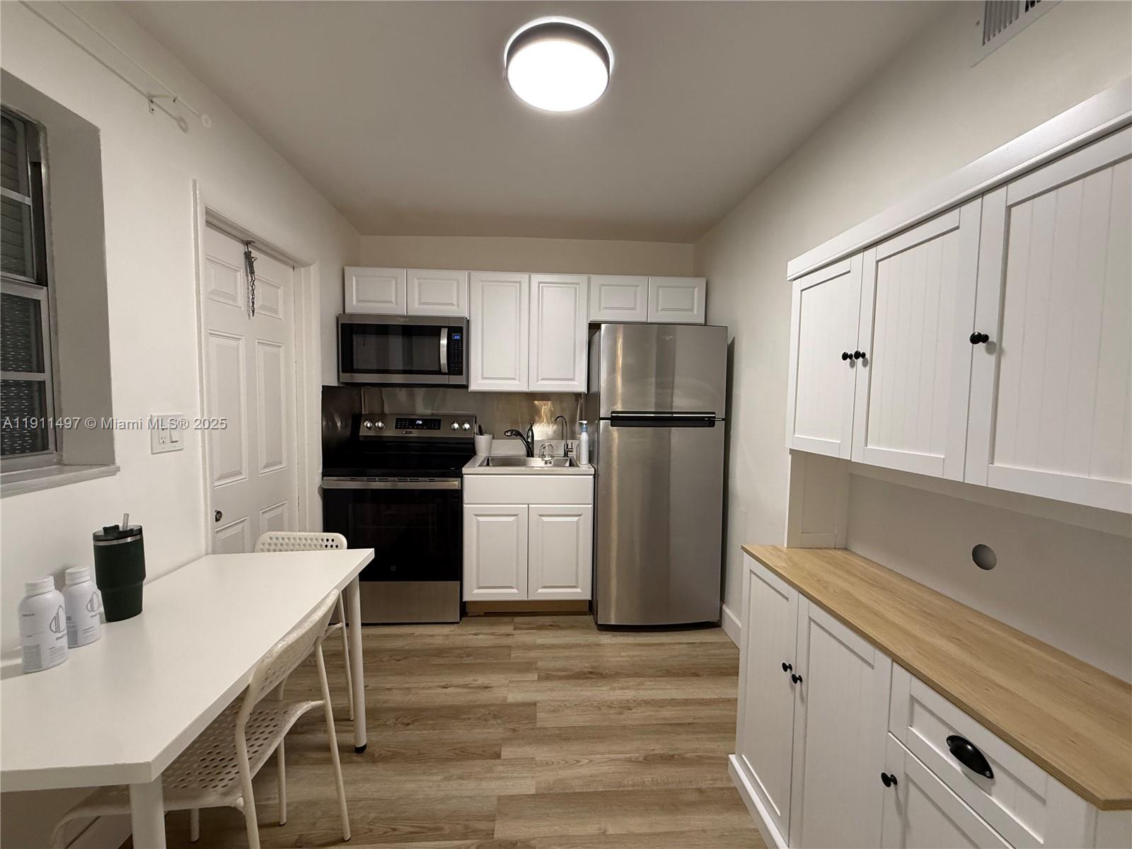 A small kitchen features white cabinetry, stainless steel appliances, and light wood-look flooring — 4310 NW 12th Ct # 302, Lauderhill FL 33313, LAUDERHILL, FL