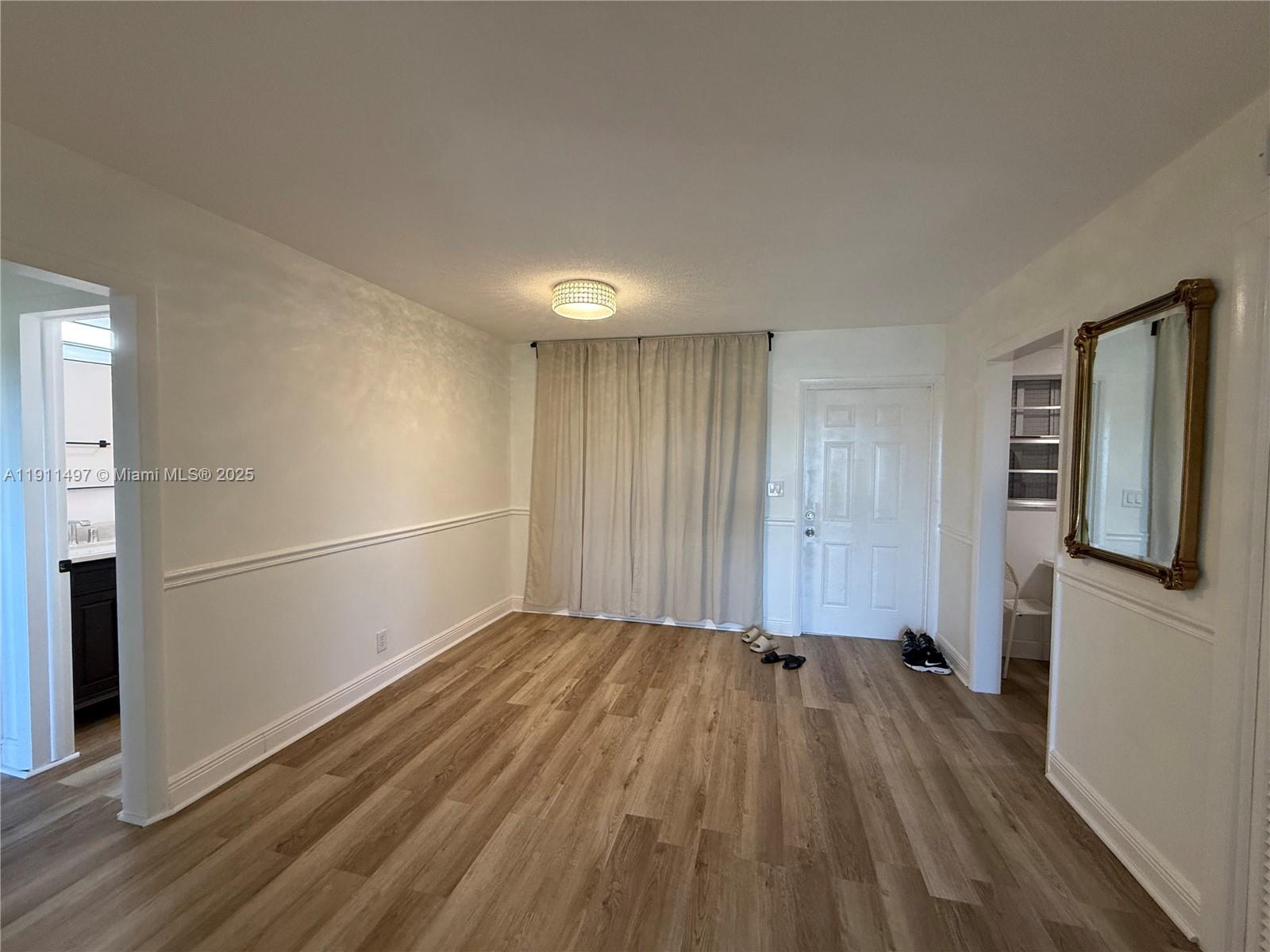 An empty room features wood-look flooring, white walls with chair rail molding, and a ceiling light — 4310 NW 12th Ct # 302, Lauderhill FL 33313, LAUDERHILL, FL