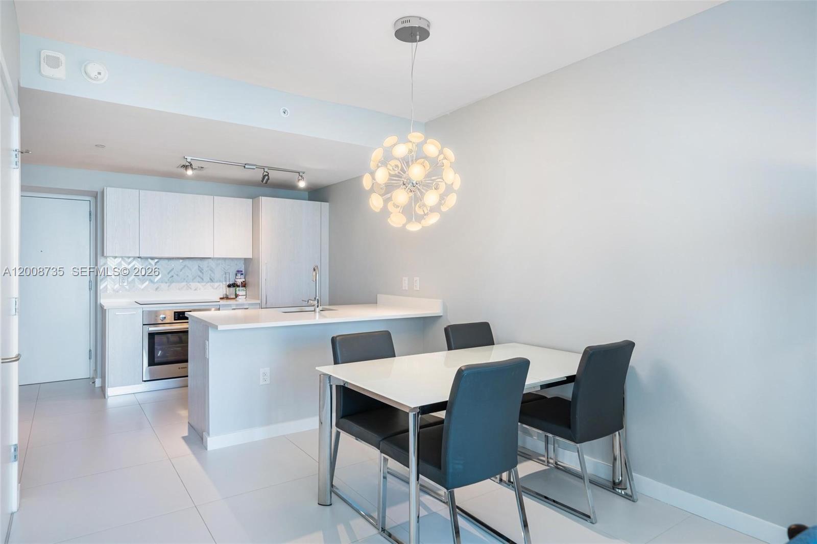 A modern kitchen with white cabinetry and a dining area featuring a contemporary chandelier — 501 NE 31st St # 2703, Miami FL 33137, MIAMI, FL