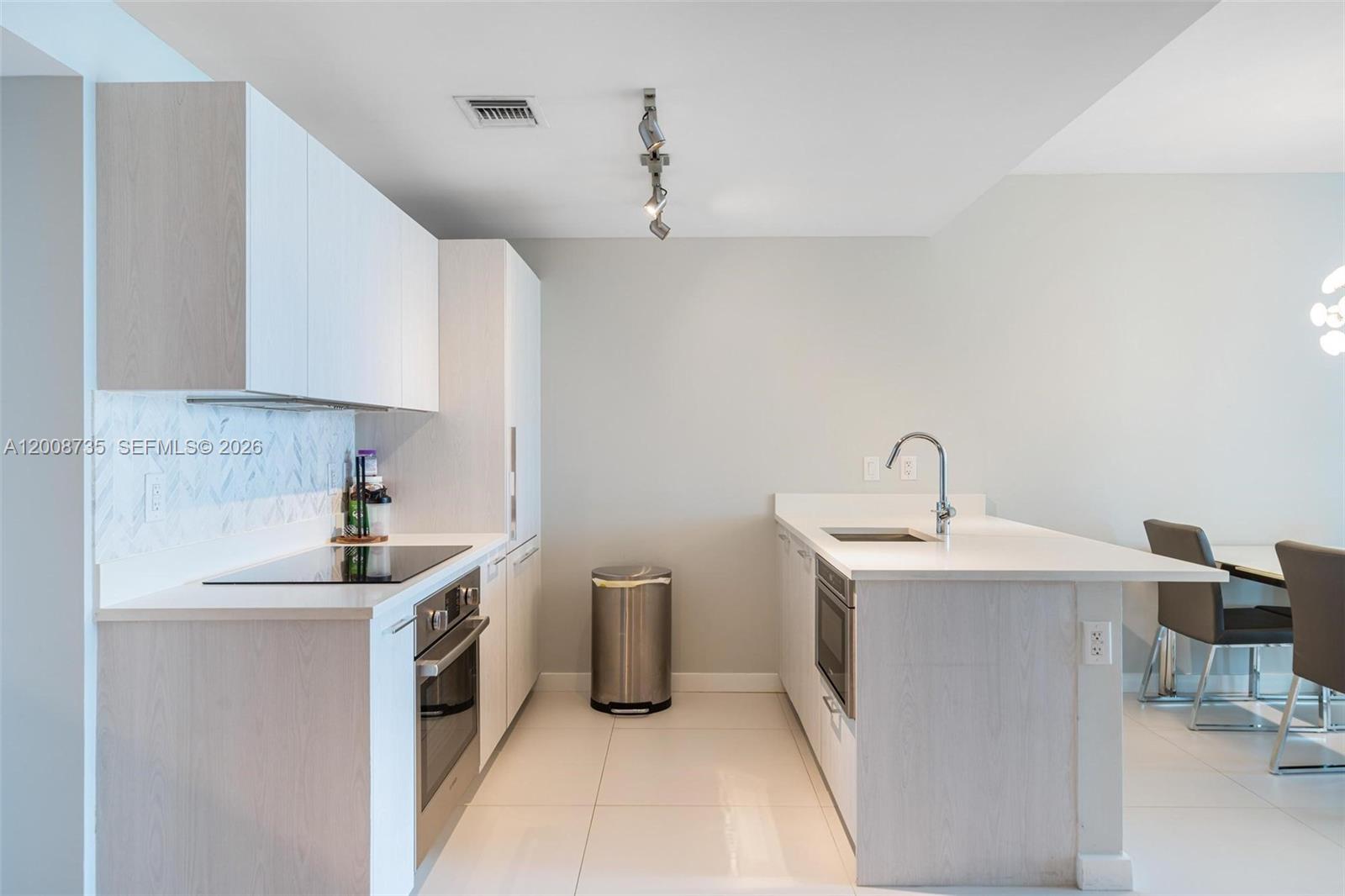 A modern kitchen features light wood cabinetry, white countertops, stainless steel appliances, and tile flooring — 501 NE 31st St # 2703, Miami FL 33137, MIAMI, FL