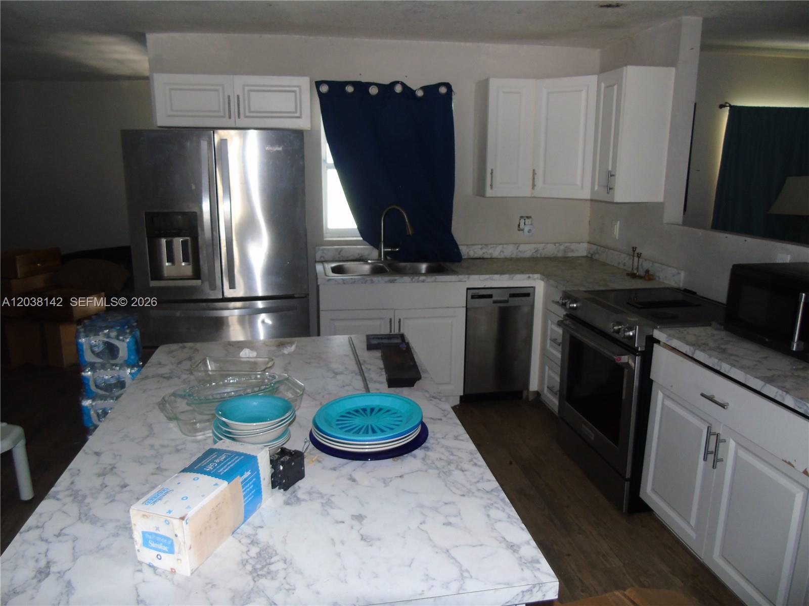 A kitchen features white cabinets, stainless steel appliances, and a marble-patterned island countertop — 1549 lime dr, Melbourne FL 32935, MELBOURNE, FL
