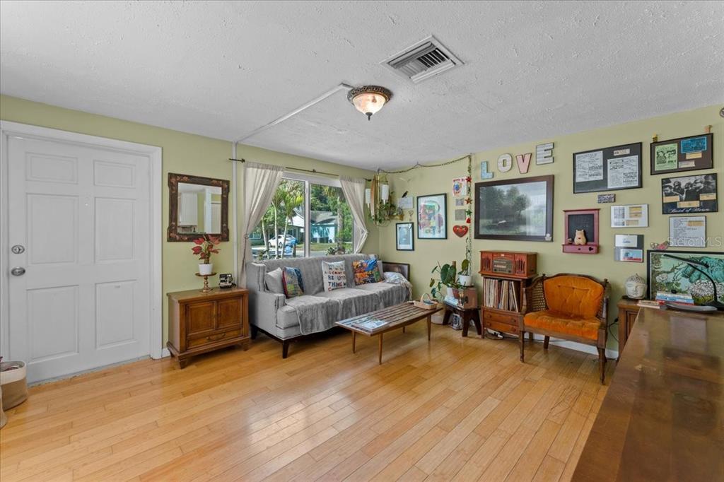 A living room features light wood flooring, a gray sofa, and a gallery wall — 531 6TH STREET S, SAFETY HARBOR, FL