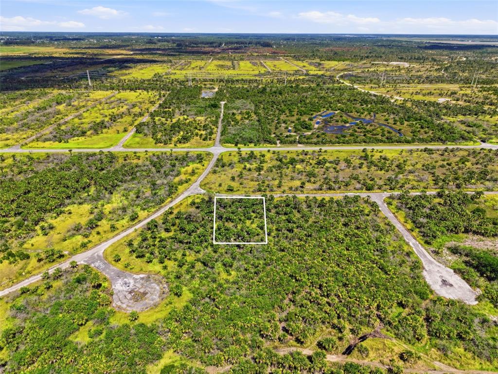 An aerial view shows a vacant, wooded lot outlined in white within a rural subdivision — 2806 FLAMEFLOWER TERRACE SW, PALM BAY, FL