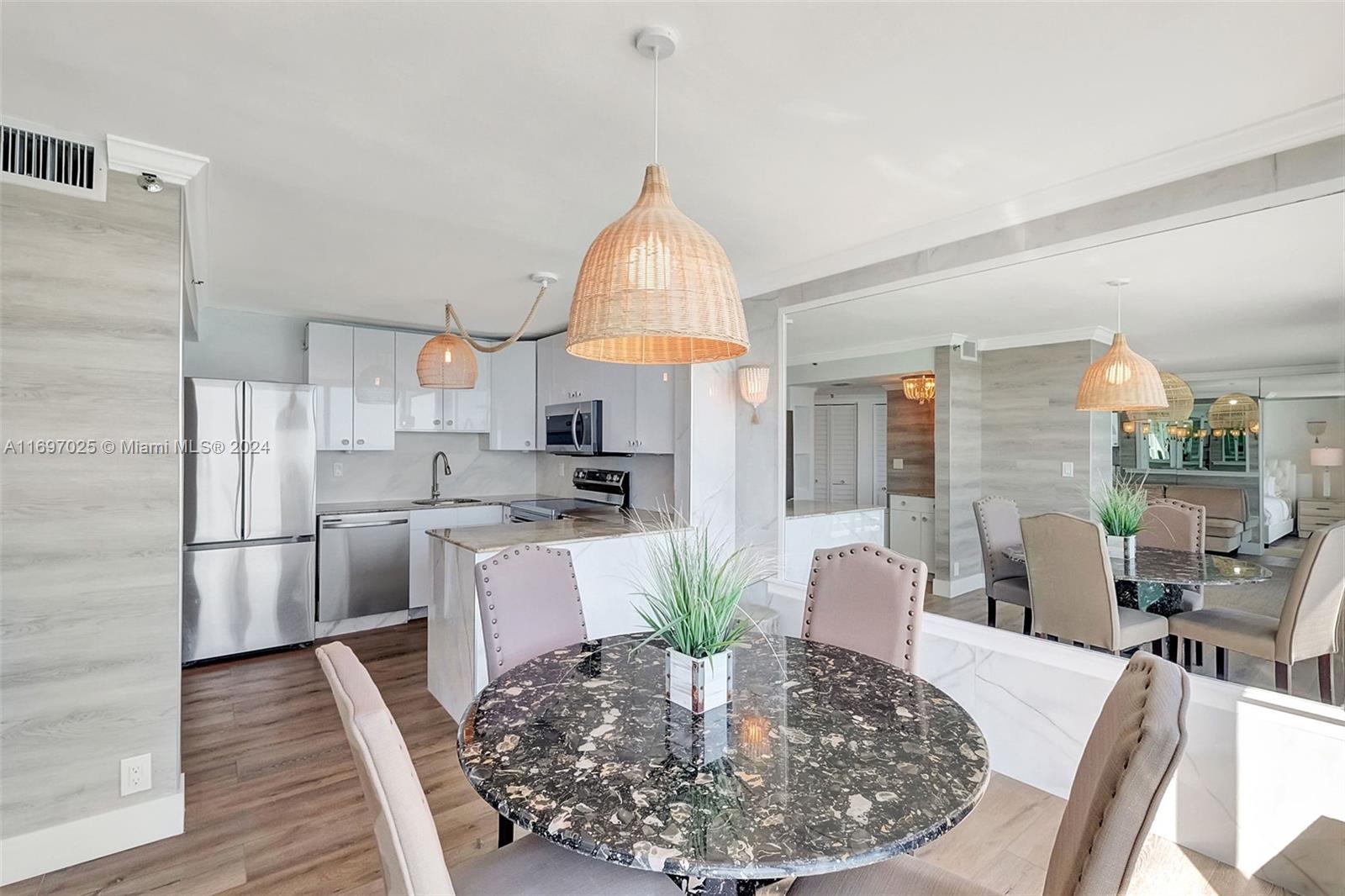 A dining area with a round stone table and chairs sits adjacent to a kitchen — 2401 Collins Ave # 1902, Miami Beach FL 33140, MIAMI BEACH, FL