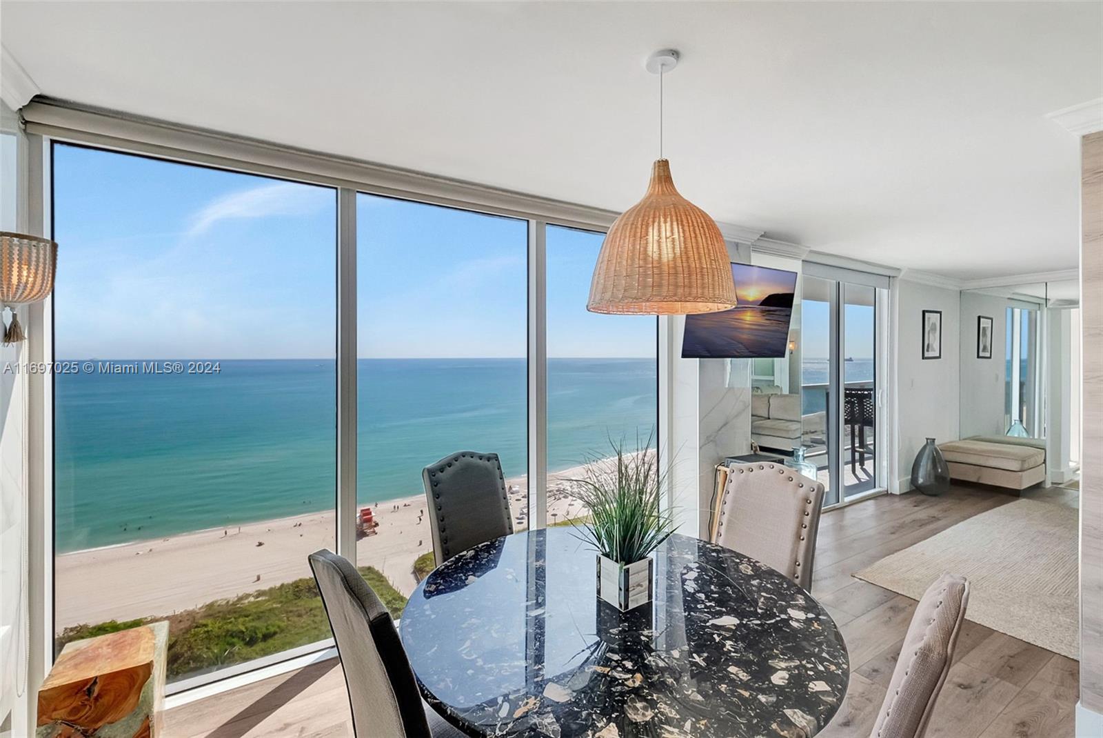 A dining area with a round marble table overlooks the ocean through floor-to-ceiling windows — 2401 Collins Ave # 1902, Miami Beach FL 33140, MIAMI BEACH, FL