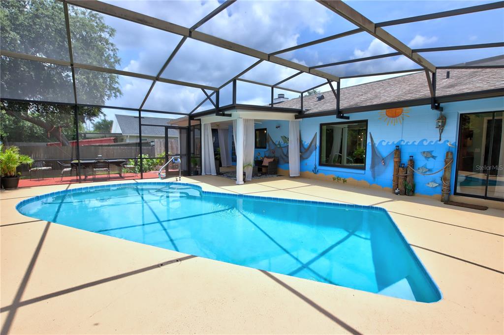 A swimming pool sits on a patio enclosed by a screened-in lanai with painted walls — 916 MENTMORE CIRCLE, DELTONA, FL