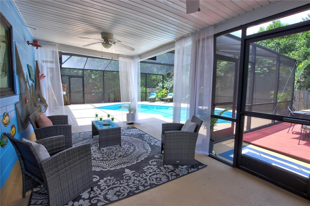 A screened-in patio features wicker furniture, a patterned rug, and a view of a pool — 916 MENTMORE CIRCLE, DELTONA, FL