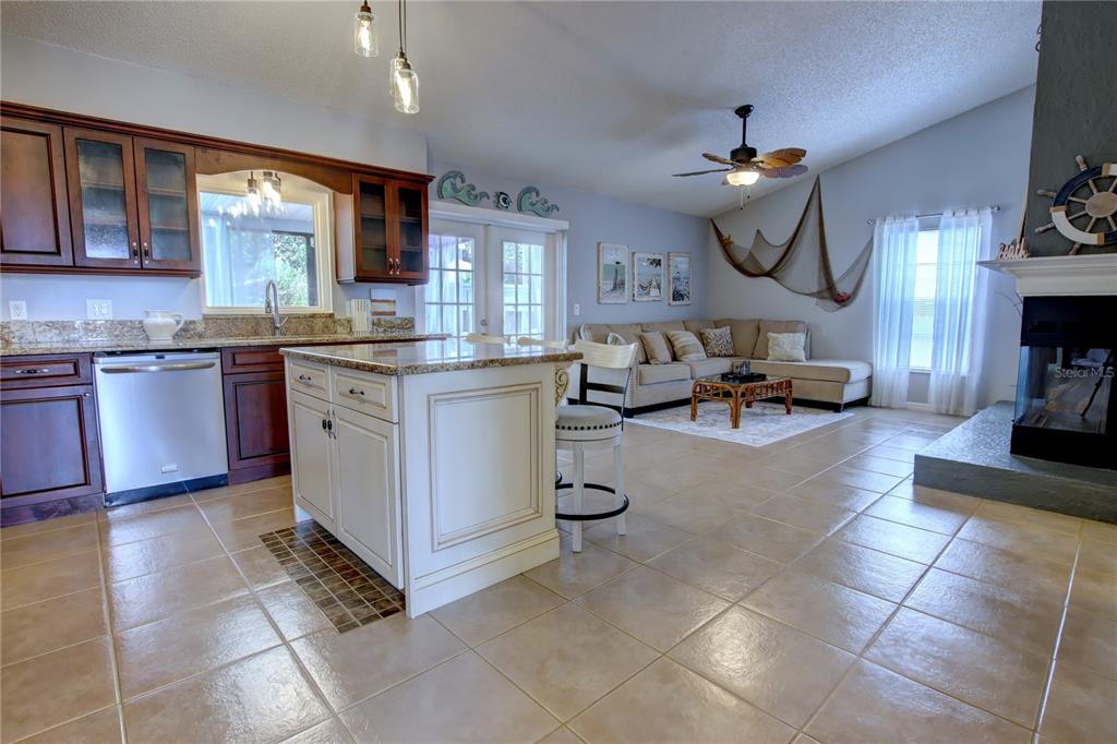 An open-concept kitchen and living area features tile floors, dark wood cabinets, and a fireplace — 916 MENTMORE CIRCLE, DELTONA, FL