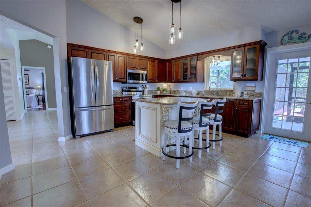A kitchen with dark wood cabinets, a central island, stainless steel appliances, and tile flooring — 916 MENTMORE CIRCLE, DELTONA, FL