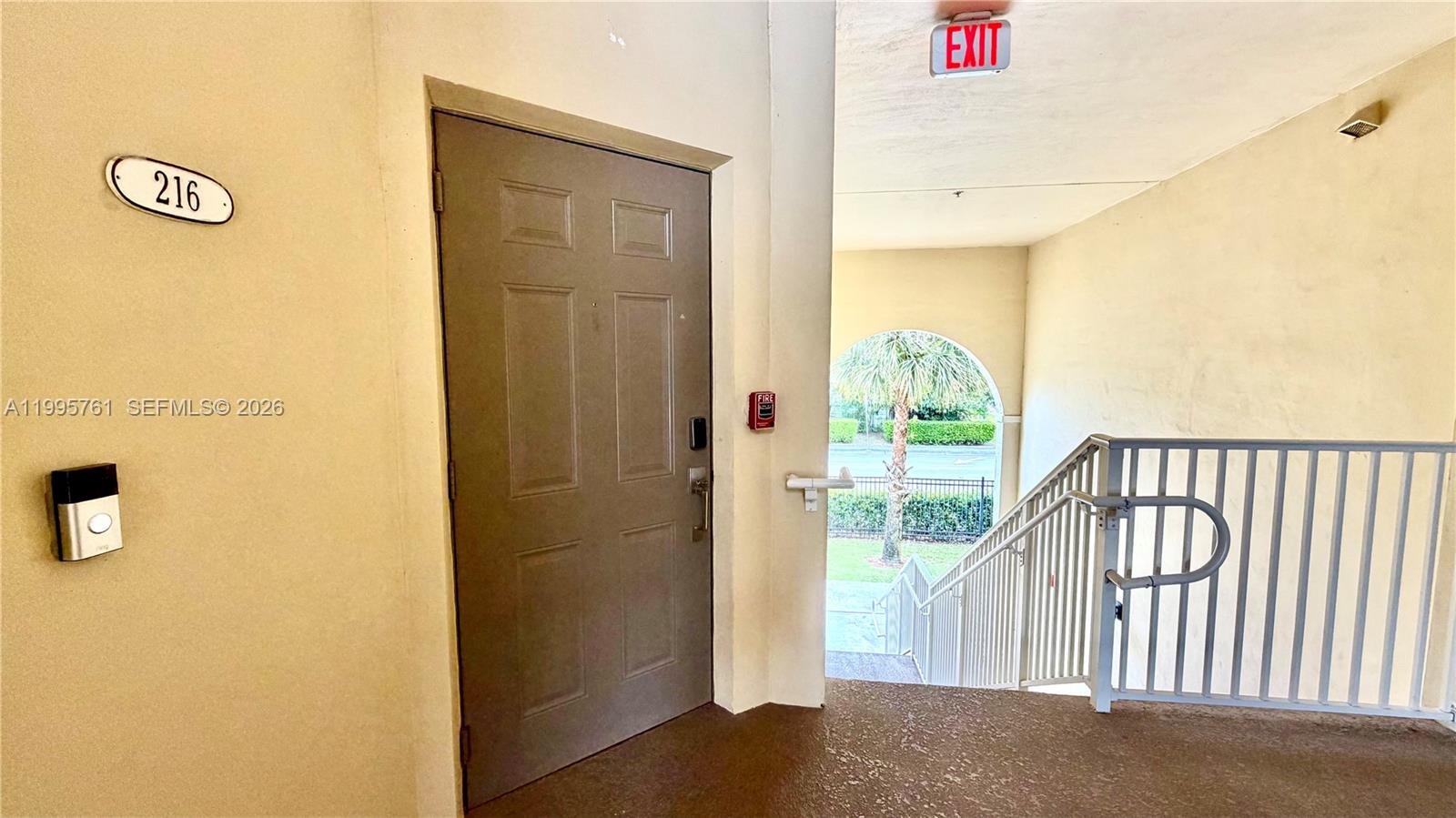 A gray door labeled 216 is located next to an outdoor staircase and exit sign — 10870 NW 88th Ter # 216, Doral FL 33178, DORAL, FL