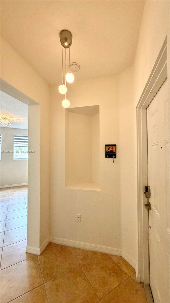 A tiled entryway features a recessed wall niche and a three-globe pendant light fixture — 10870 NW 88th Ter # 216, Doral FL 33178, DORAL, FL
