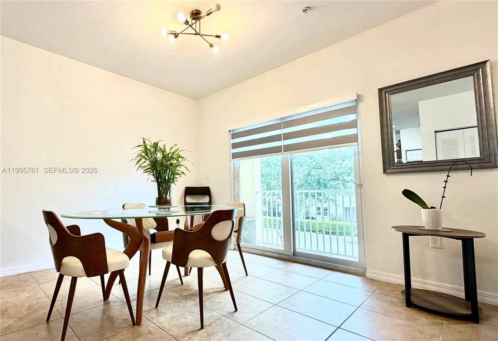 A dining room features a glass-topped table, modern chairs, tile flooring, and a sliding door — 10870 NW 88th Ter # 216, Doral FL 33178, DORAL, FL