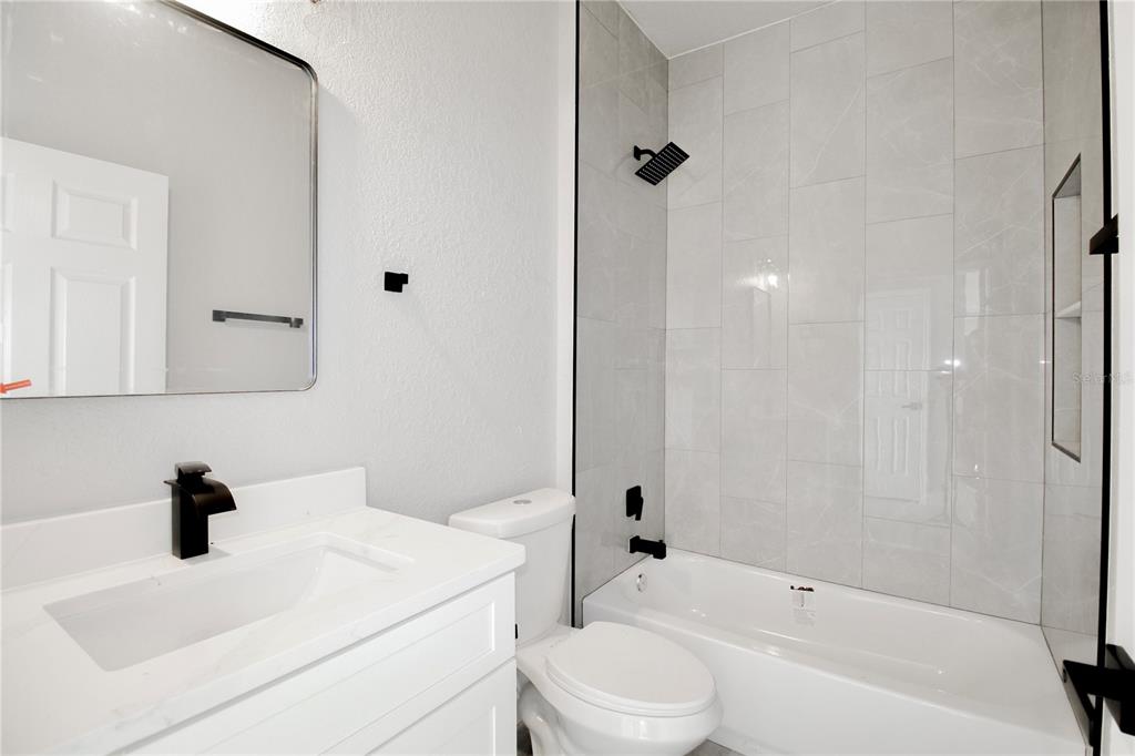 A modern kitchen features white cabinets, stainless steel appliances, a center island, and pendant lighting — 4608 CORTEZ BOULEVARD, SEBRING, FL