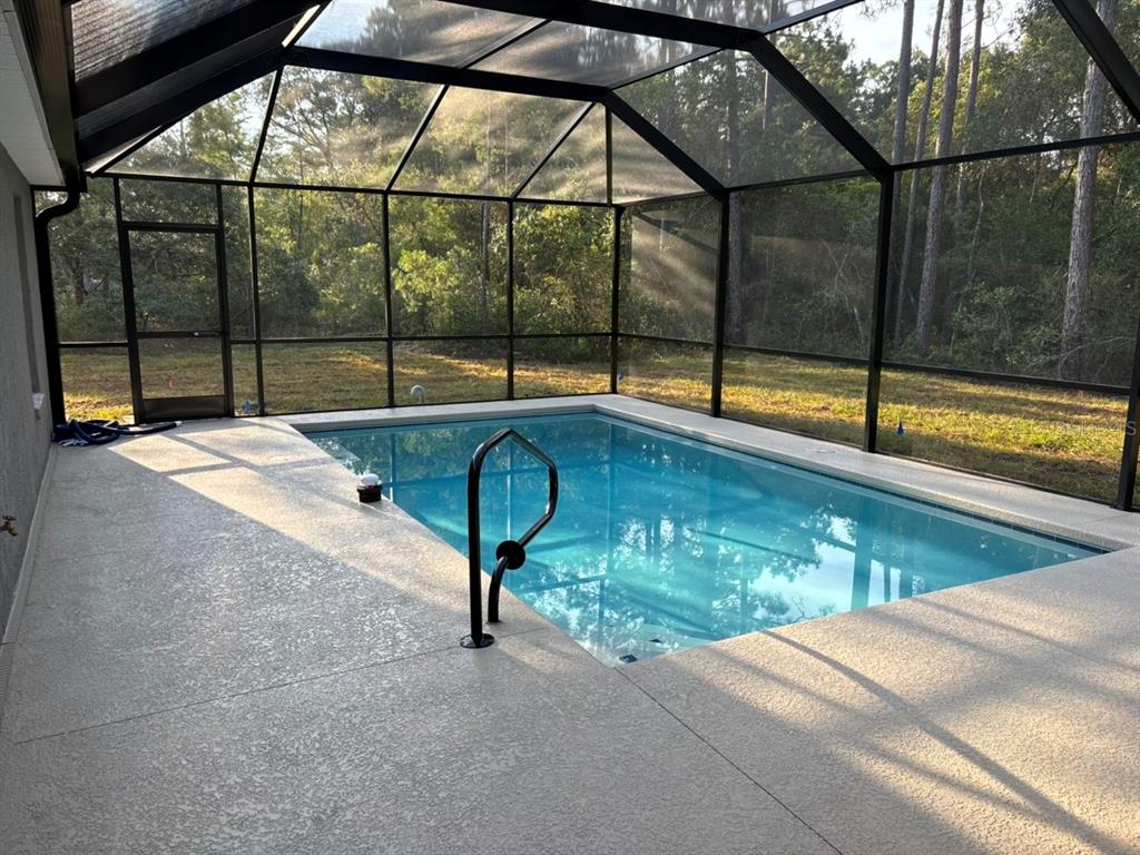 A rectangular swimming pool is enclosed by a screened lanai with a concrete deck — 4888 W MAVERICK COURT, BEVERLY HILLS, FL