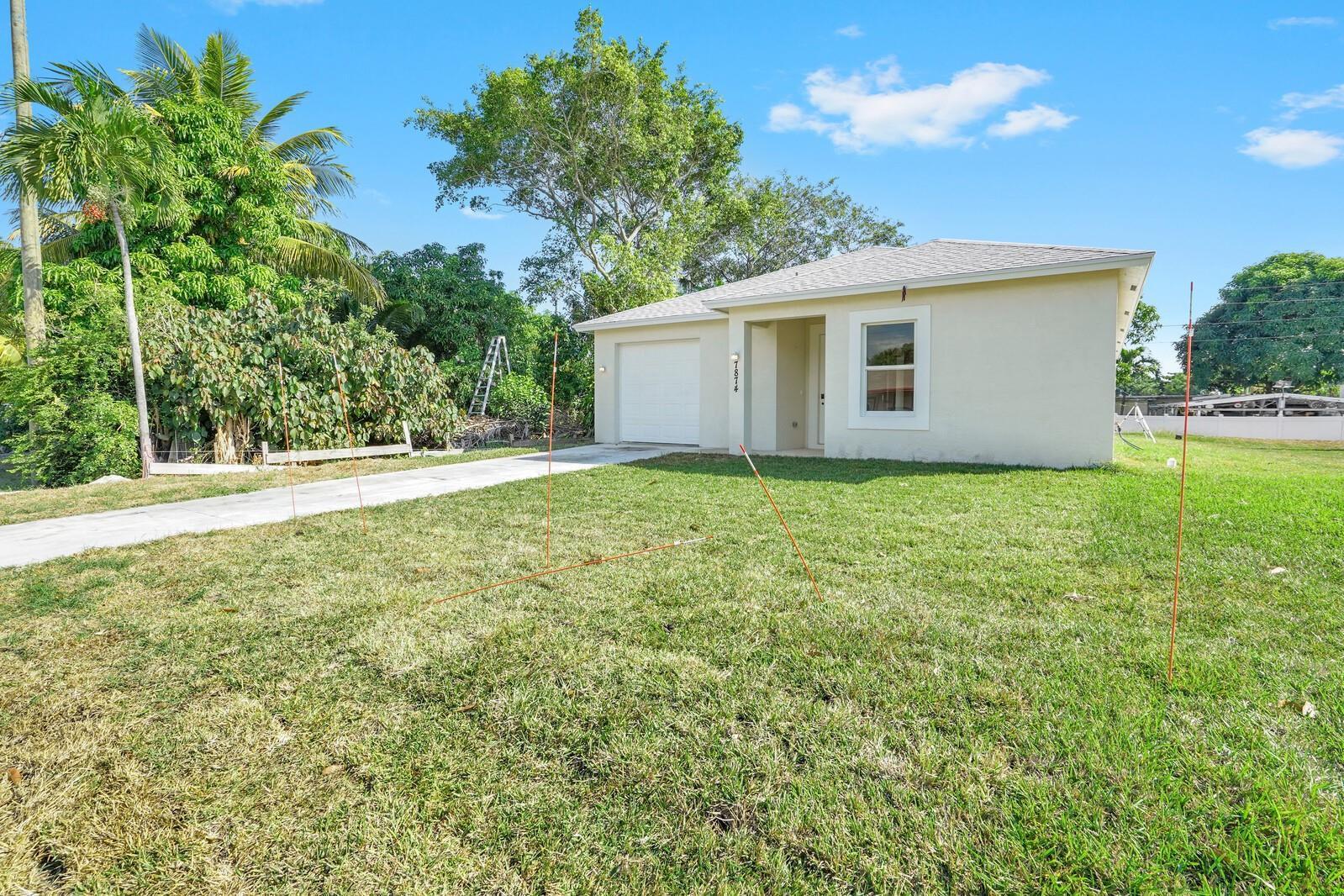 A single-story house with a garage and a large front lawn under a blue sky — 7874 Griswold Street, Lantana FL 33462, LANTANA, FL