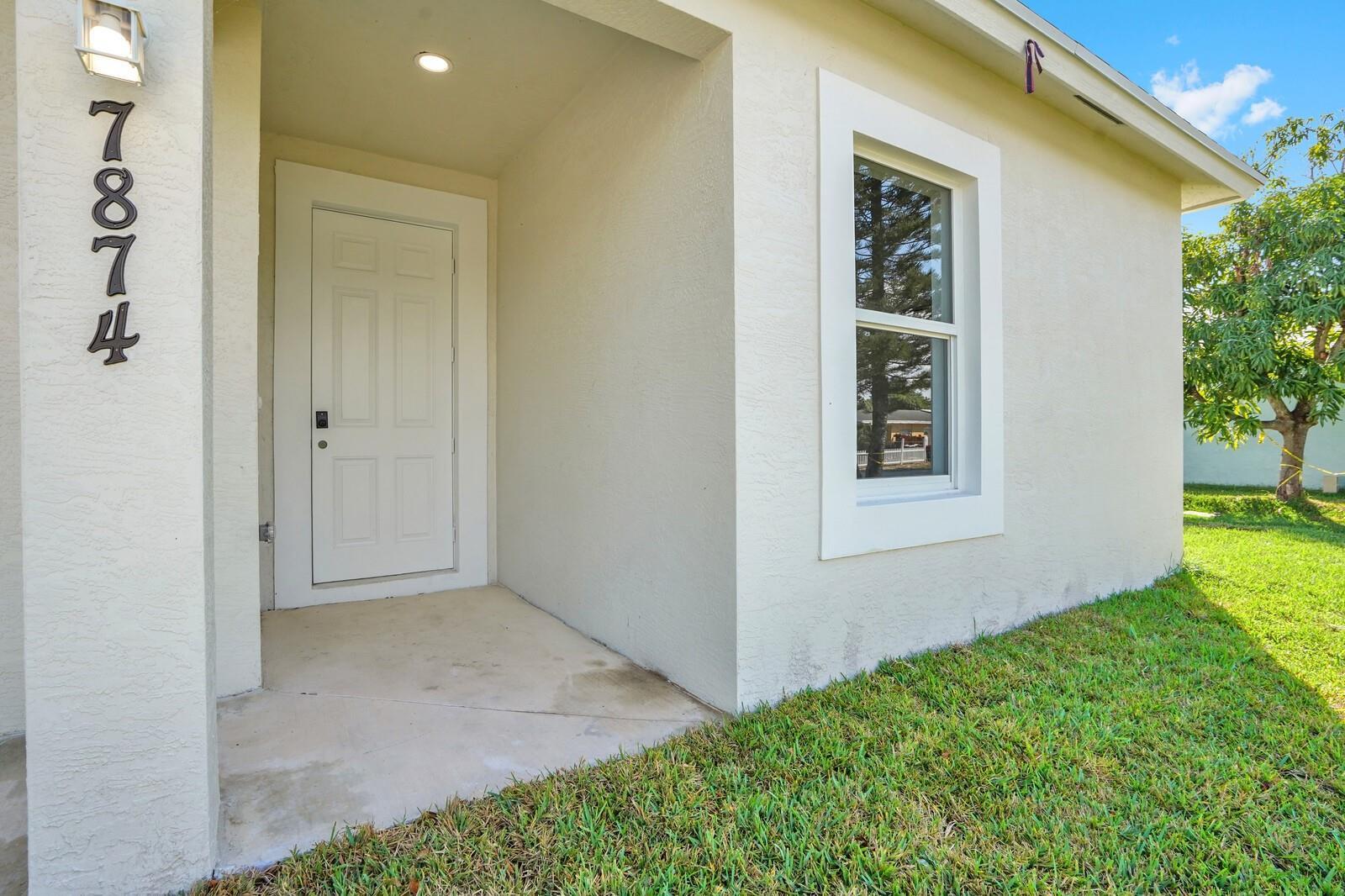 A white front door and a window are visible on the exterior of a house — 7874 Griswold Street, Lantana FL 33462, LANTANA, FL