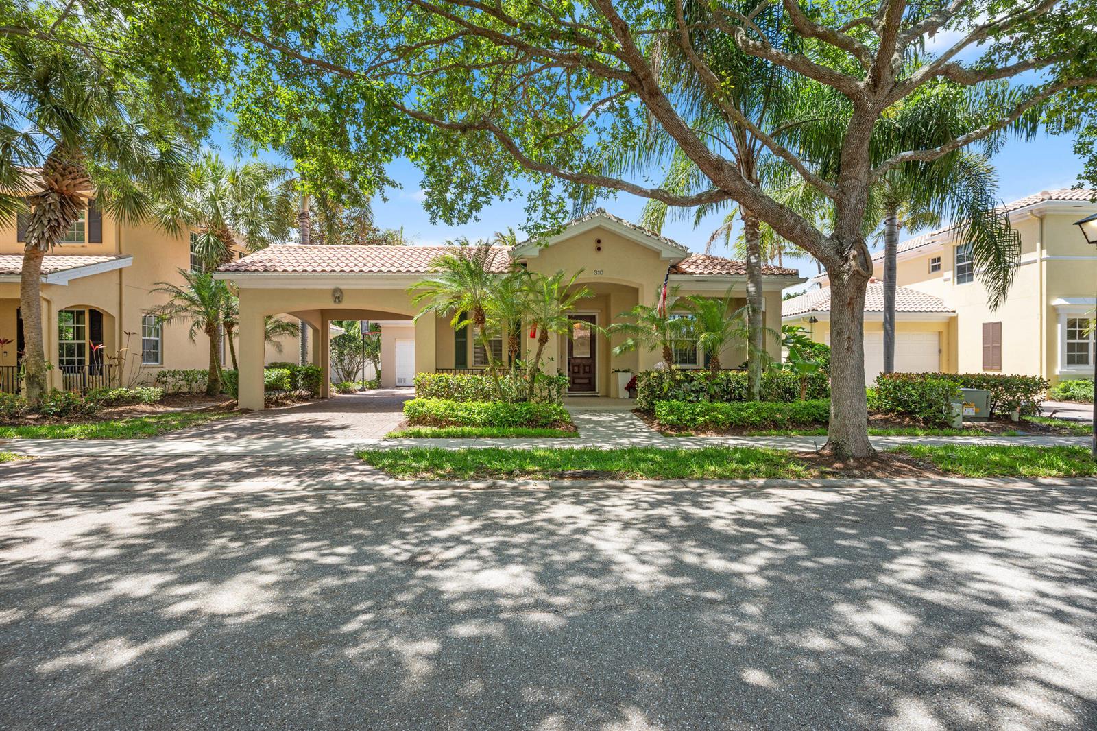 A single-story house with a tiled roof, a covered carport, and mature trees in front — 310 San Remo Drive, Jupiter FL 33458, JUPITER, FL