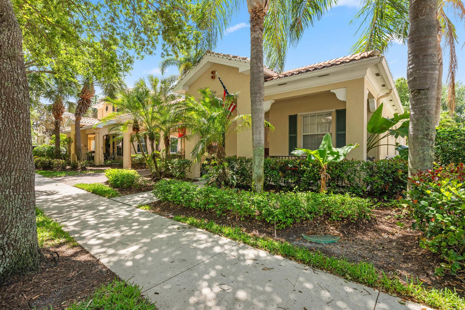 A tan stucco house with a tiled roof, front porch, and lush landscaping along a sidewalk — 310 San Remo Drive, Jupiter FL 33458, JUPITER, FL