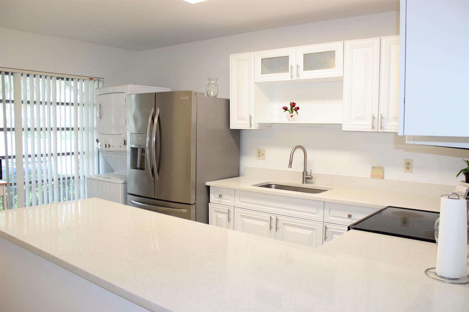 A kitchen with white cabinets, stainless steel appliances, and a quartz countertop island — 8573 Boca Drive # 3, Boca Raton FL 33433, BOCA RATON, FL
