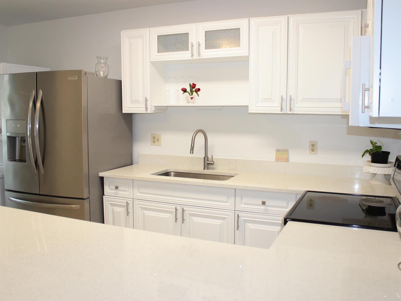 A kitchen features white cabinets, stainless steel appliances, and light-colored countertops with a sink — 8573 Boca Drive # 3, Boca Raton FL 33433, BOCA RATON, FL