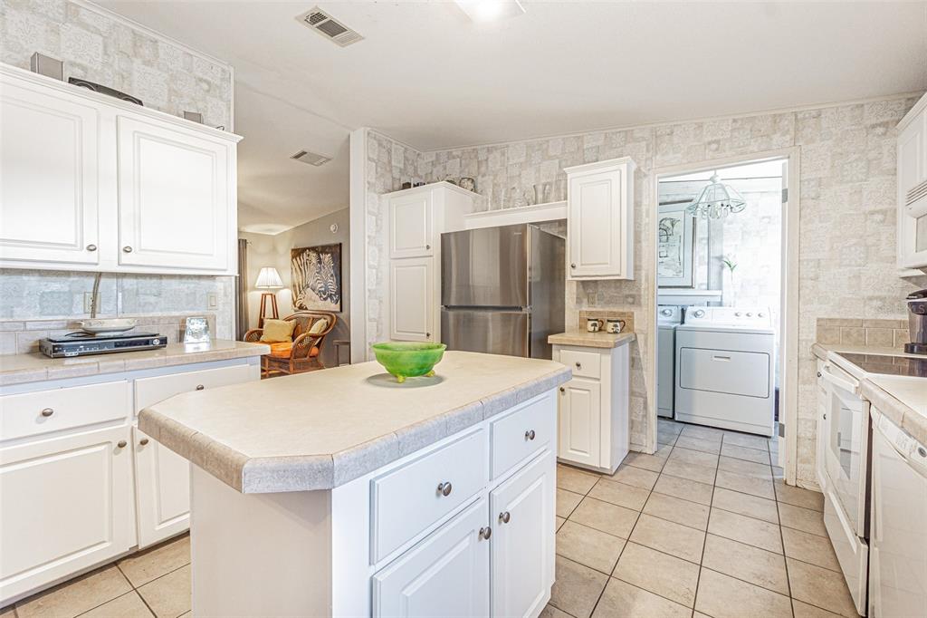 A kitchen features white cabinets, a central island with a tiled countertop, and stainless appliances — 37627 LORENA AVENUE, ZEPHYRHILLS, FL