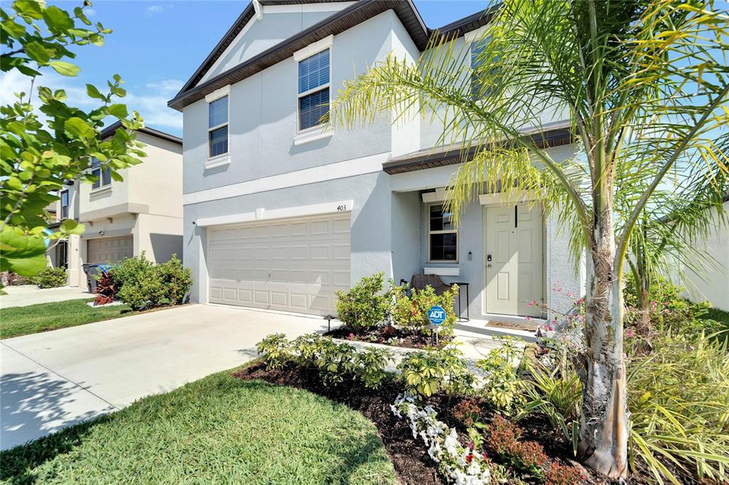 A two-story light blue house with a two-car garage and a front palm tree — 403 ROYAL EMPRESS DRIVE, RUSKIN, FL