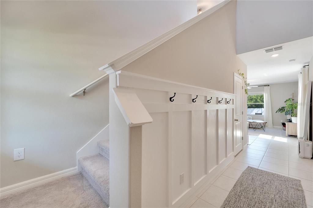 A staircase with white wainscoting and coat hooks leads to a tiled hallway — 403 ROYAL EMPRESS DRIVE, RUSKIN, FL
