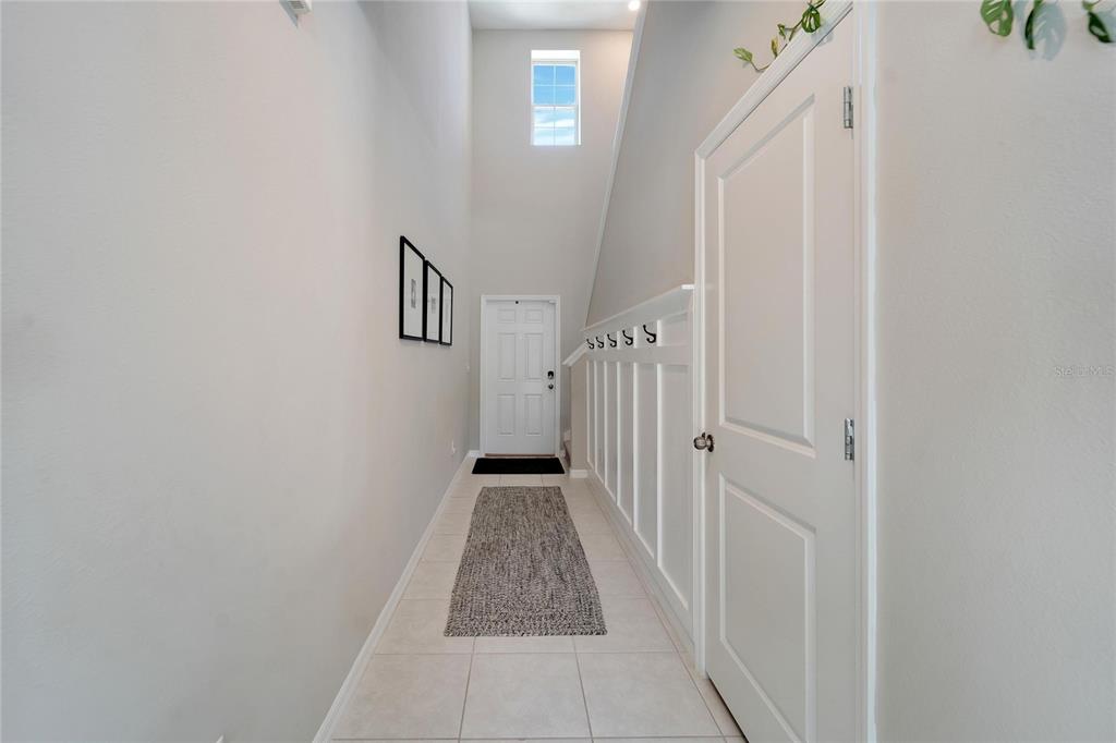 A bright entryway features a high ceiling, white wainscoting with coat hooks, and tile flooring — 403 ROYAL EMPRESS DRIVE, RUSKIN, FL