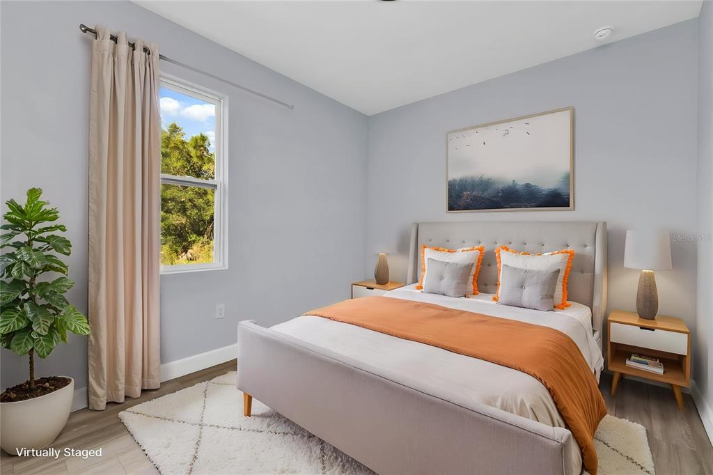 A bedroom features a bed with orange bedding, a window with curtains, and a potted plant — 71 STANHOPE STREET, PORT CHARLOTTE, FL