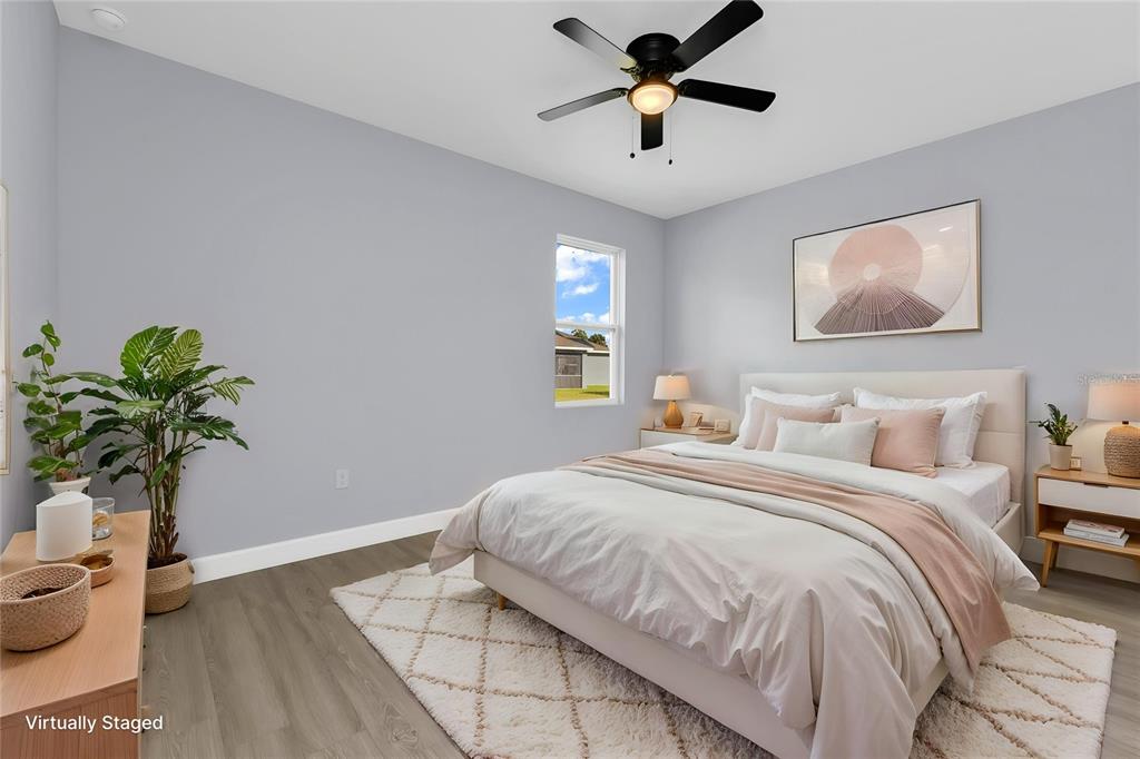 A virtually staged bedroom features light gray walls, wood-look flooring, and a ceiling fan — 71 STANHOPE STREET, PORT CHARLOTTE, FL