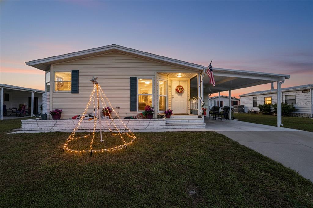 A single-story mobile home with beige siding, a carport, and a lighted lawn decoration — 512 LA PLAYA CIRCLE, NORTH PORT, FL