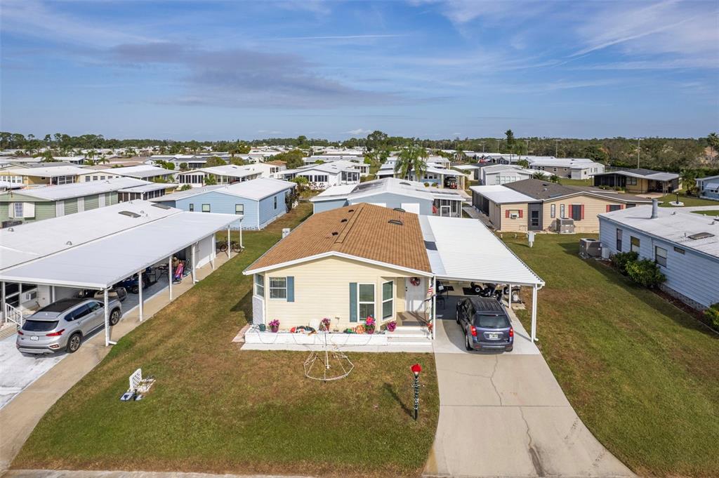 An aerial view of a yellow manufactured home with a brown roof and attached carport — 512 LA PLAYA CIRCLE, NORTH PORT, FL