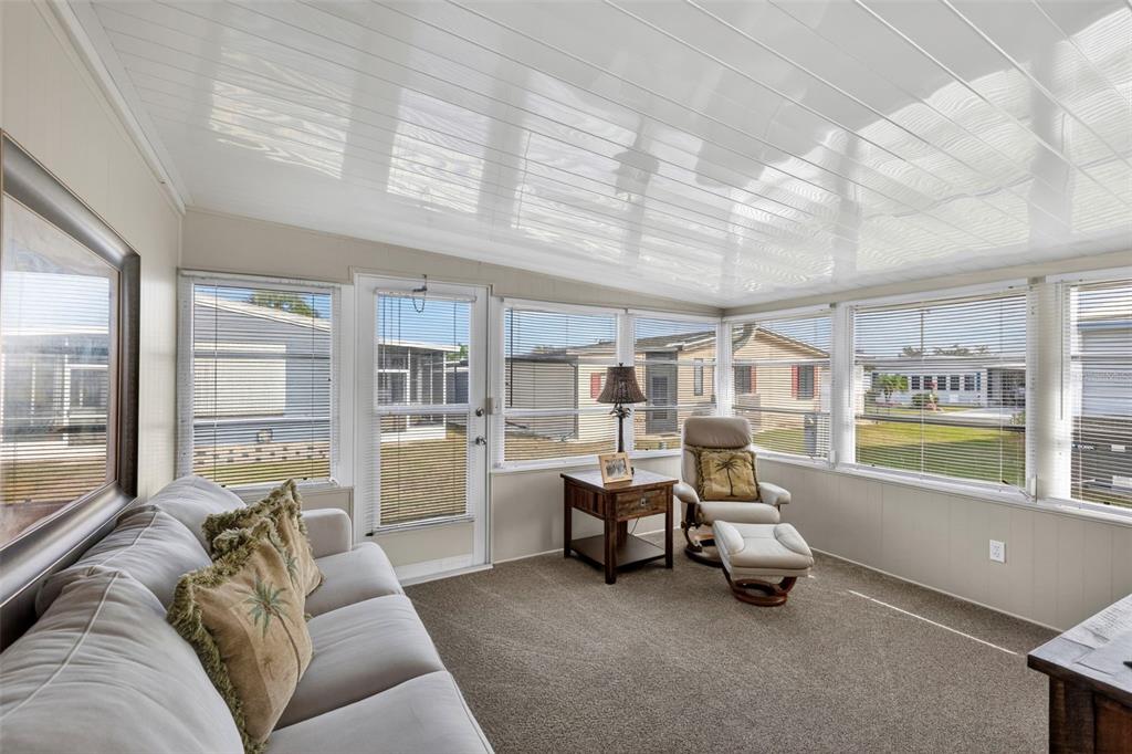 A sunroom features a beige sofa, a recliner with ottoman, and large windows with blinds — 512 LA PLAYA CIRCLE, NORTH PORT, FL