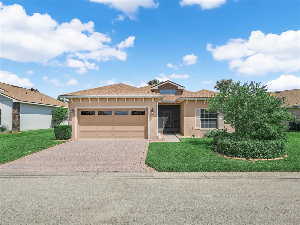 A single-story house with a tan stucco exterior, a two-car garage, and a paved driveway — 5308 GREEN DRIVE, WINTER HAVEN, FL