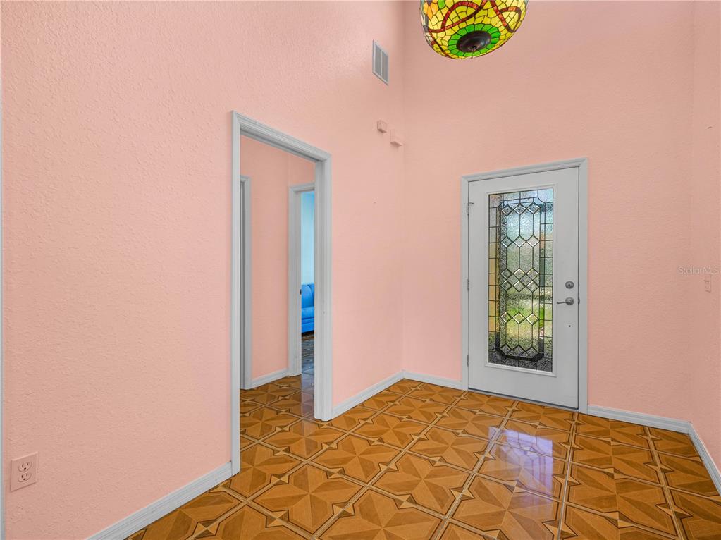 An entryway with pink walls, a stained-glass light fixture, and patterned tile flooring — 5308 GREEN DRIVE, WINTER HAVEN, FL