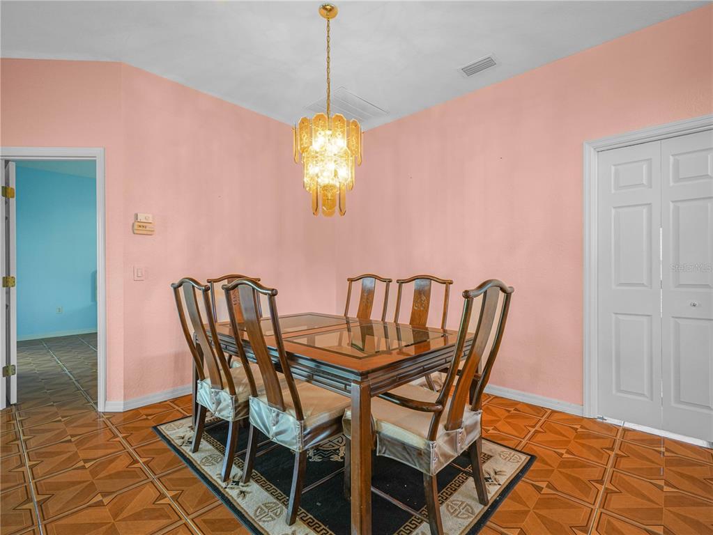 A dining room features a wooden table with six chairs, a chandelier, and pink walls — 5308 GREEN DRIVE, WINTER HAVEN, FL