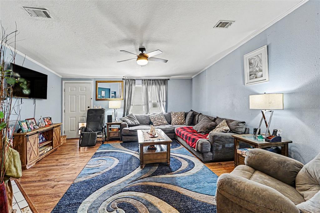 A living room features a sectional sofa, a patterned area rug, and a television console — 38030 LAWANDA LOOP, ZEPHYRHILLS, FL