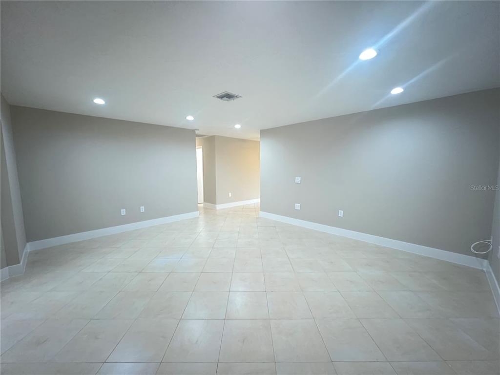 An empty room features light-colored tile flooring, neutral walls, and recessed ceiling lighting — 20250 MIDWAY BOULEVARD, PORT CHARLOTTE, FL