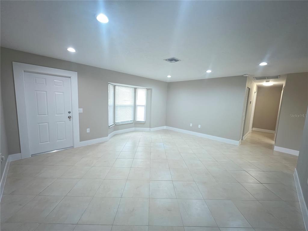 A spacious room features light-colored tile flooring, beige walls, recessed lighting, and a bay window — 20250 MIDWAY BOULEVARD, PORT CHARLOTTE, FL
