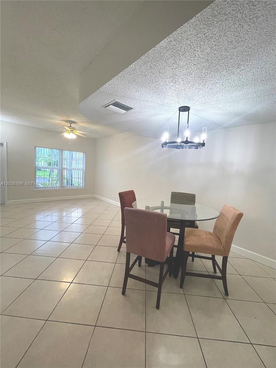 A dining area features a glass-topped table, four chairs, tile flooring, and a chandelier — 3100 SW 50th St, Dania Beach FL 33312, DANIA BEACH, FL