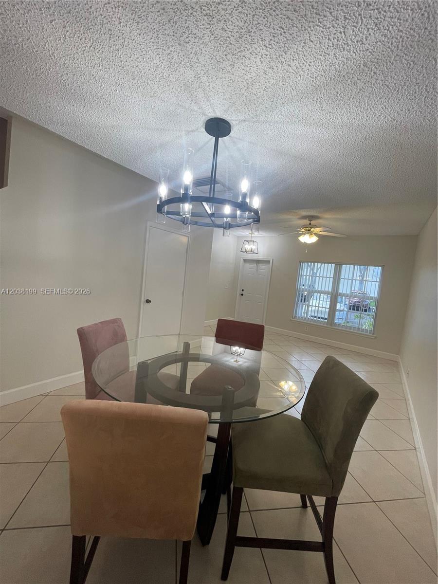 A dining area features a glass-topped table, four upholstered chairs, and a modern chandelier — 3100 SW 50th St, Dania Beach FL 33312, DANIA BEACH, FL