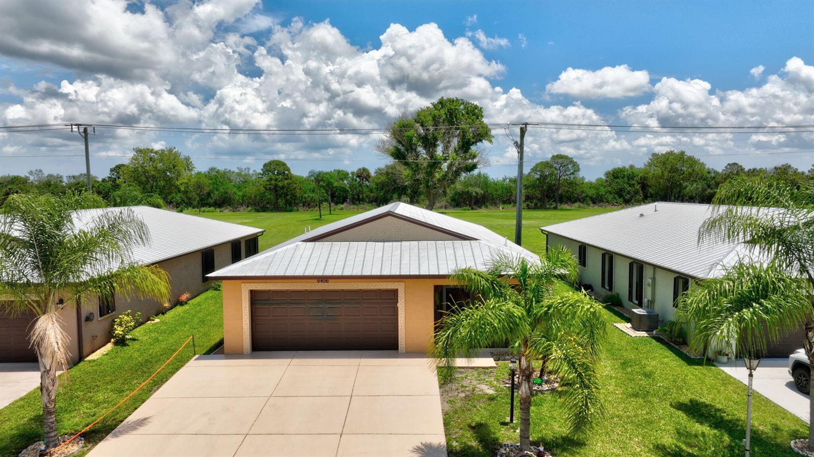 An aerial view shows a single-story house with a metal roof and a concrete driveway — 6456 Alemendra, Fort Pierce FL 34951, FORT PIERCE, FL