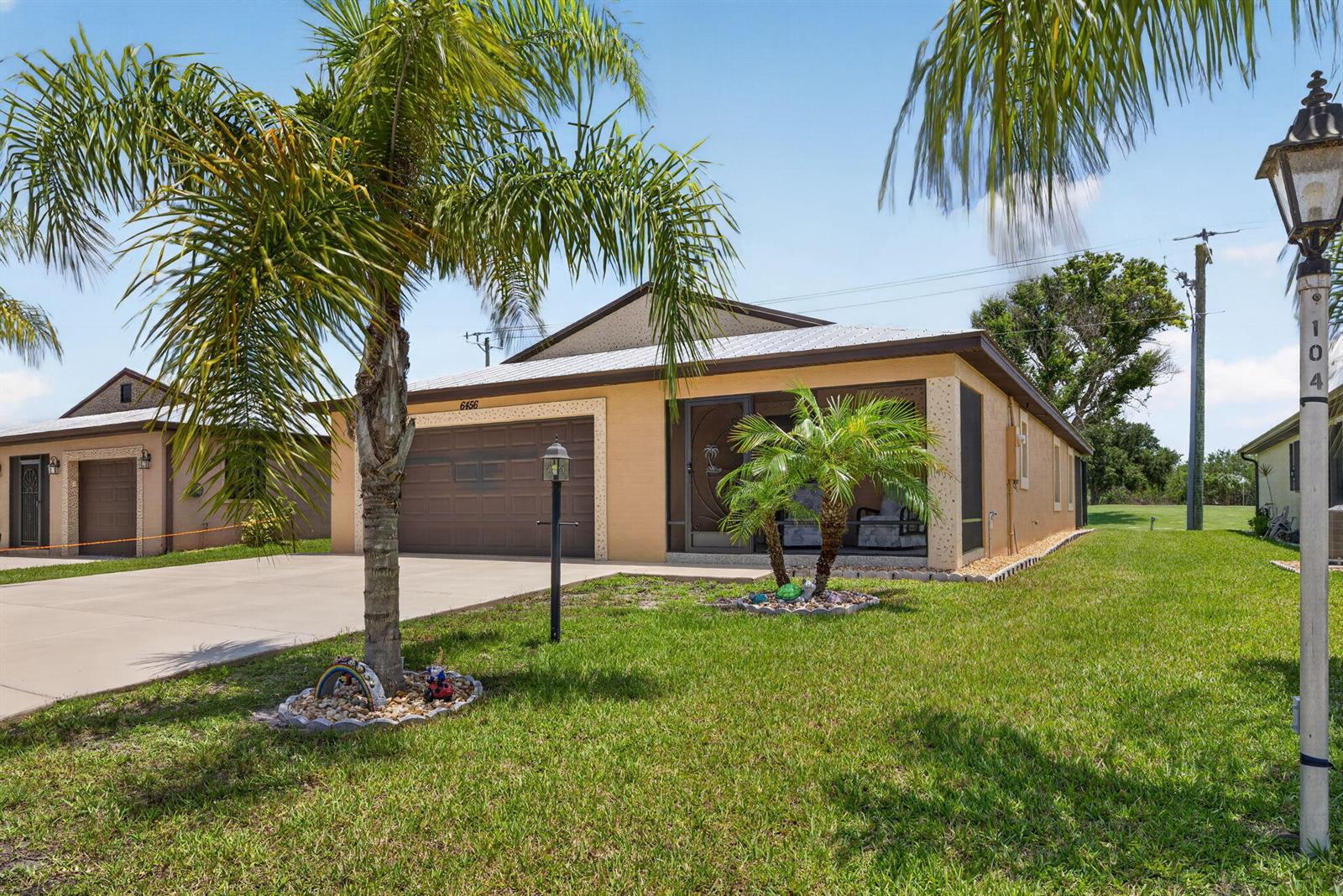 A single-story house with a tan stucco exterior, a two-car garage, and a screened porch — 6456 Alemendra, Fort Pierce FL 34951, FORT PIERCE, FL