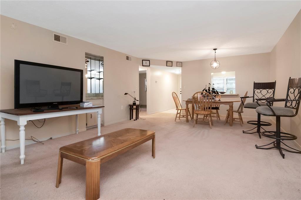 A living and dining area features beige carpet, a television on a table, and furniture — 7725 FOREST TRAIL UNIT 2, PORT RICHEY, FL