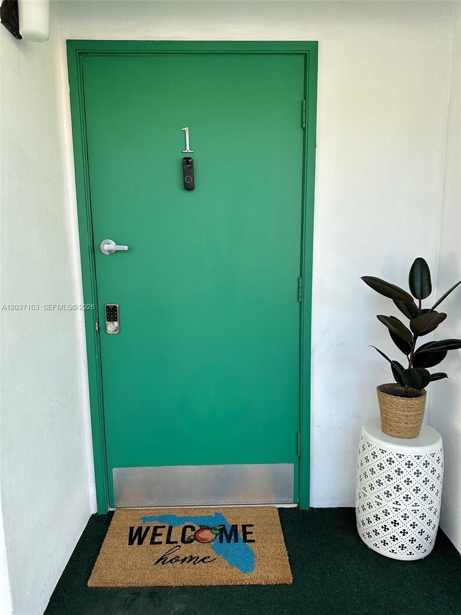 A green front door with the number one sits beside a potted plant and mat — 5301 Ocean Ter # 1, Marathon FL 33050, MARATHON, FL