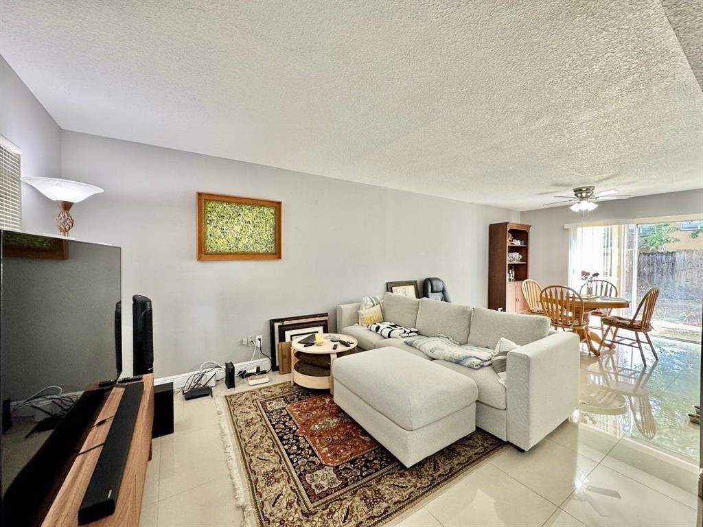 A living room features a light gray sectional sofa, a patterned area rug, and a dining area — 5216 TENNIS COURT CIRCLE UNIT 5216, TAMPA, FL
