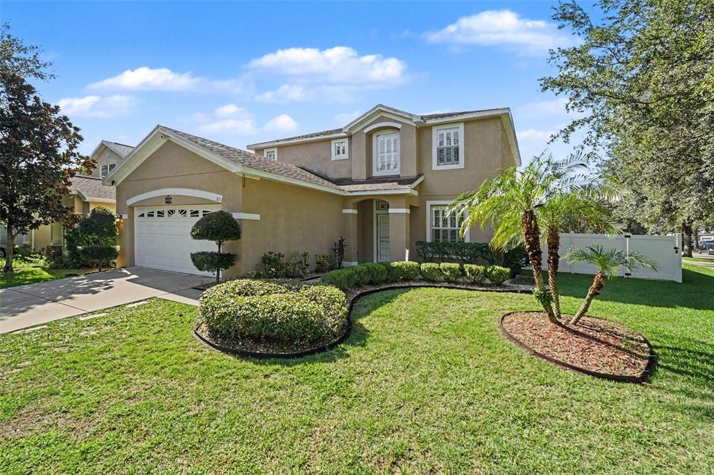 A two-story suburban house with a tan stucco exterior, a garage, and a landscaped front yard — 301 FERN GULLEY DRIVE, SEFFNER, FL